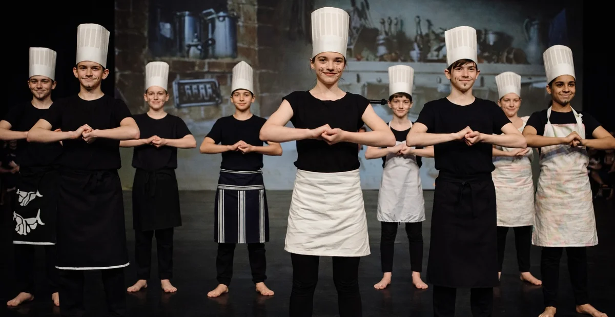 Drama students dressed as chefs performing in class production