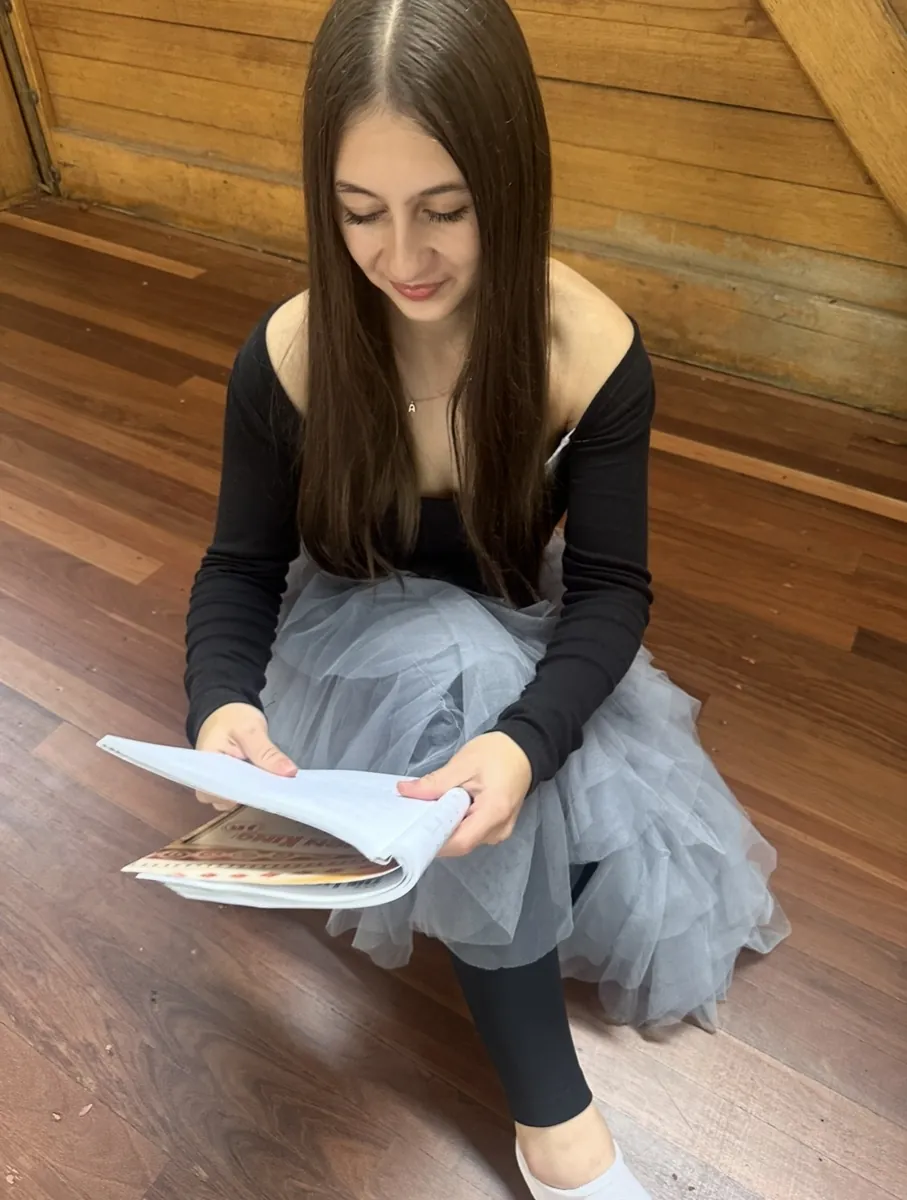 Student in costume reading a script during a speech and drama class
