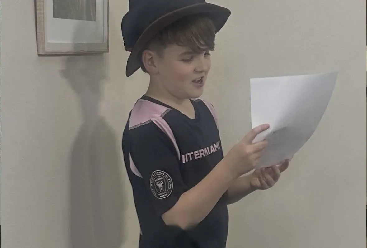 Student in a hat reading a script during a speech and drama class