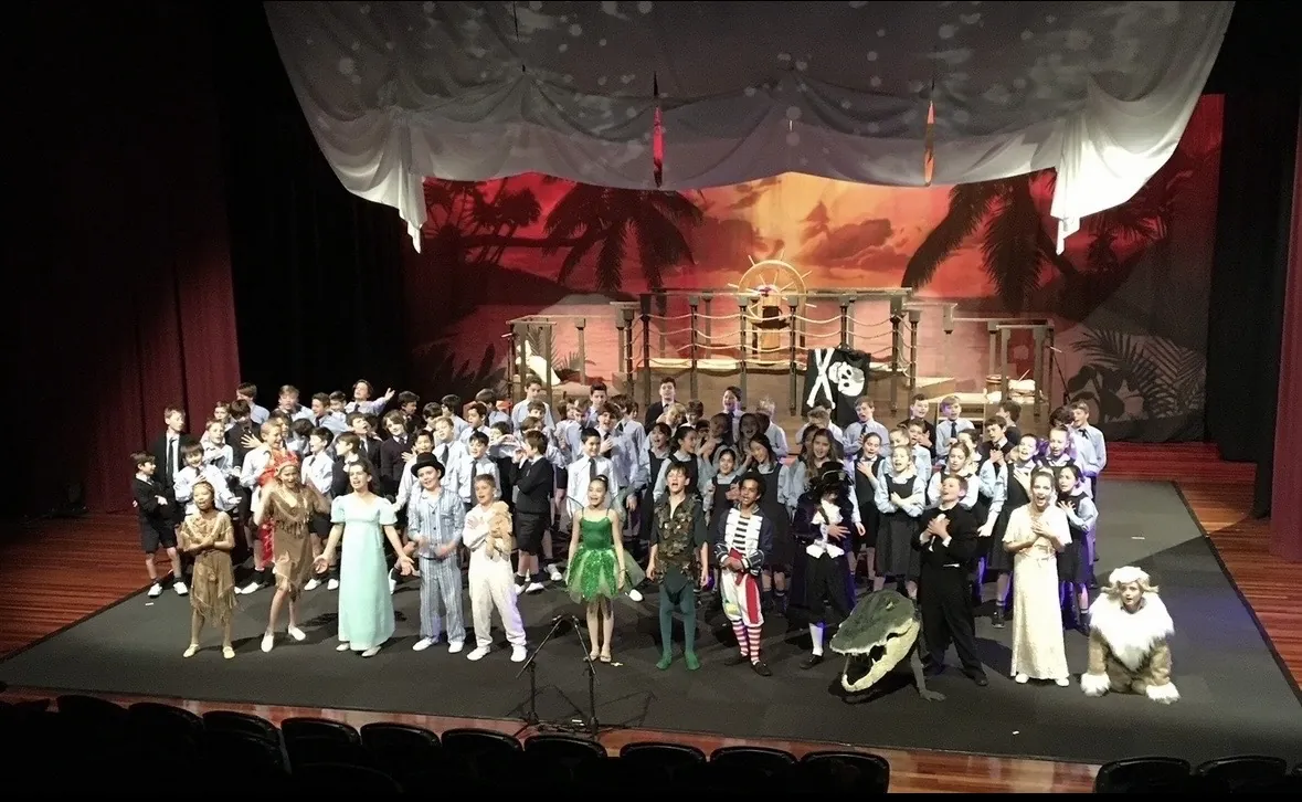 Full cast performing on stage during a school production directed by Ranges Studio