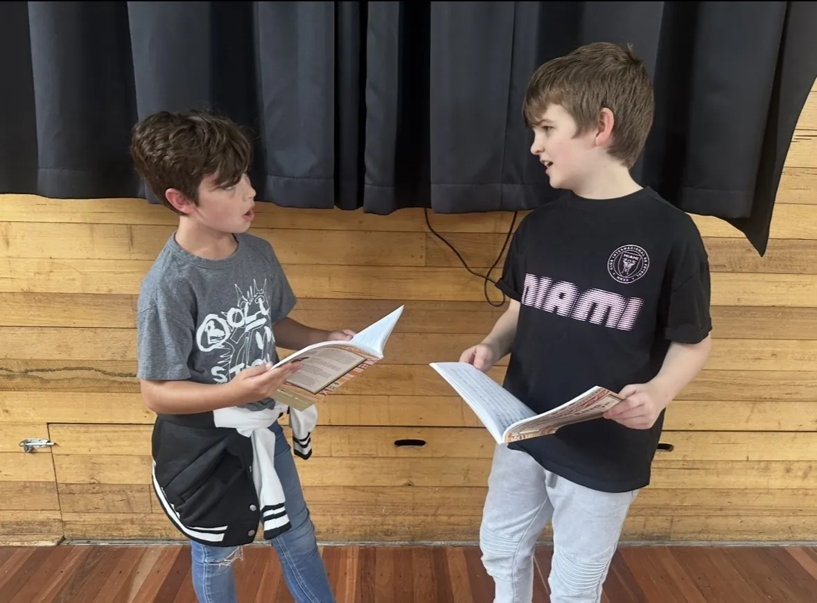 Two students rehearsing a scene with scripts at a speech and drama class