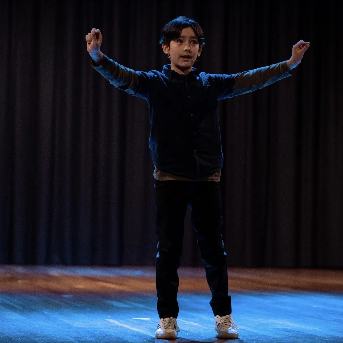 Speech and drama student performing on stage with arms outstretched