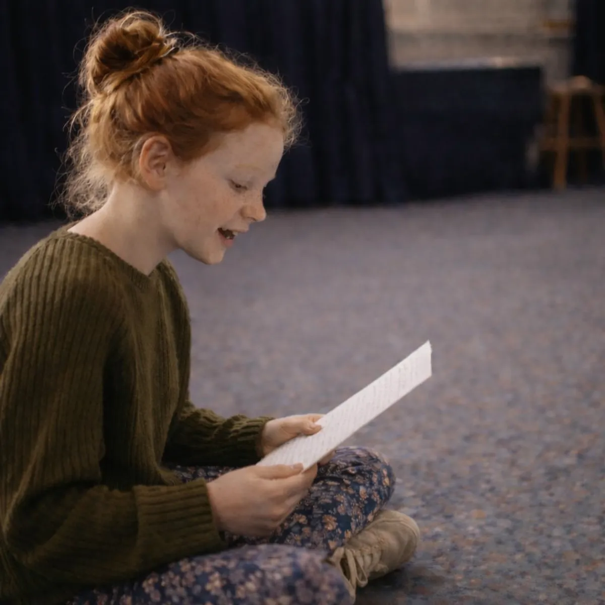 Young girl sitting on floor reading aloud during speech and drama class at Ranges Studio