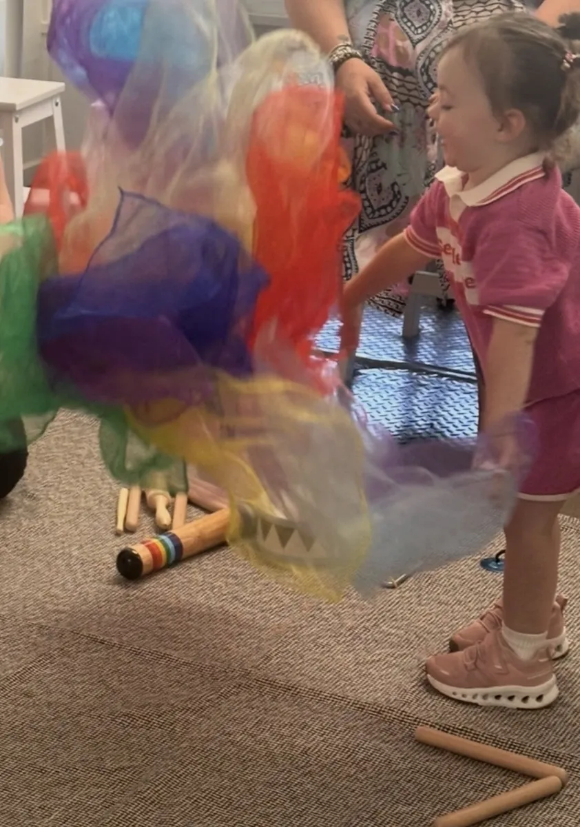 Young child playing with colourful scarves during Tell and Show class at Ranges Studio