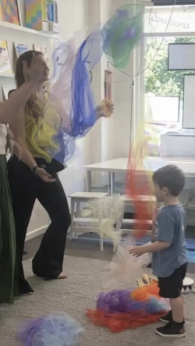Teacher and young student playing with scarves in Tell and Show drama class