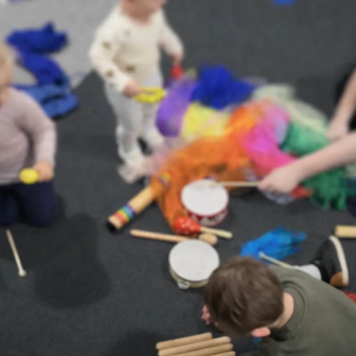 Toddlers playing drums and instruments together during Tell and Show group activity