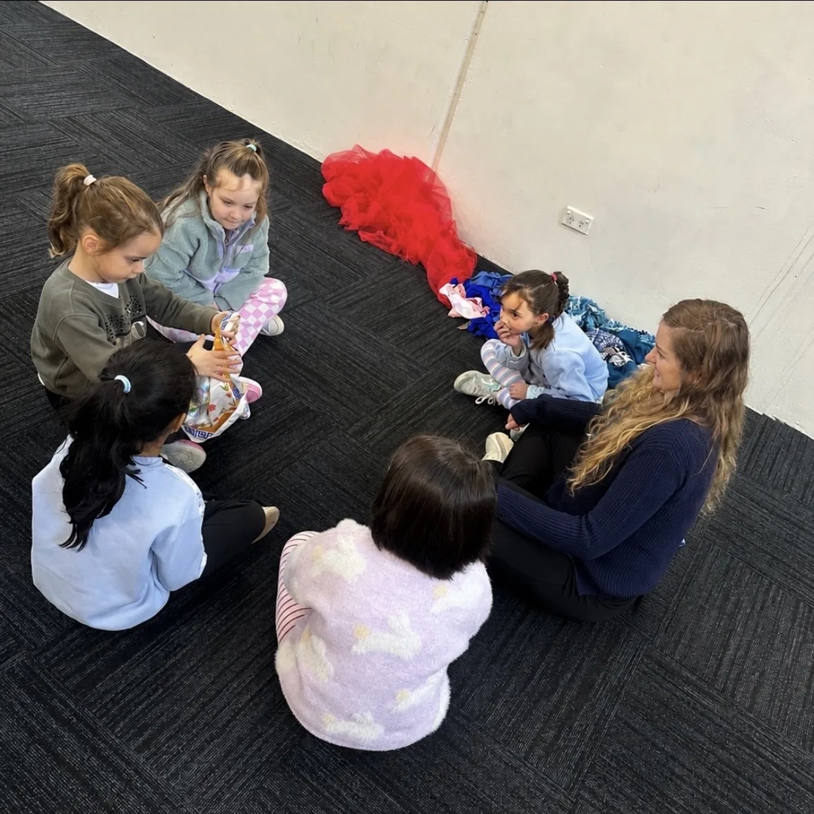 Early learners playing on the floor with dolls and props at a Tell & Show class