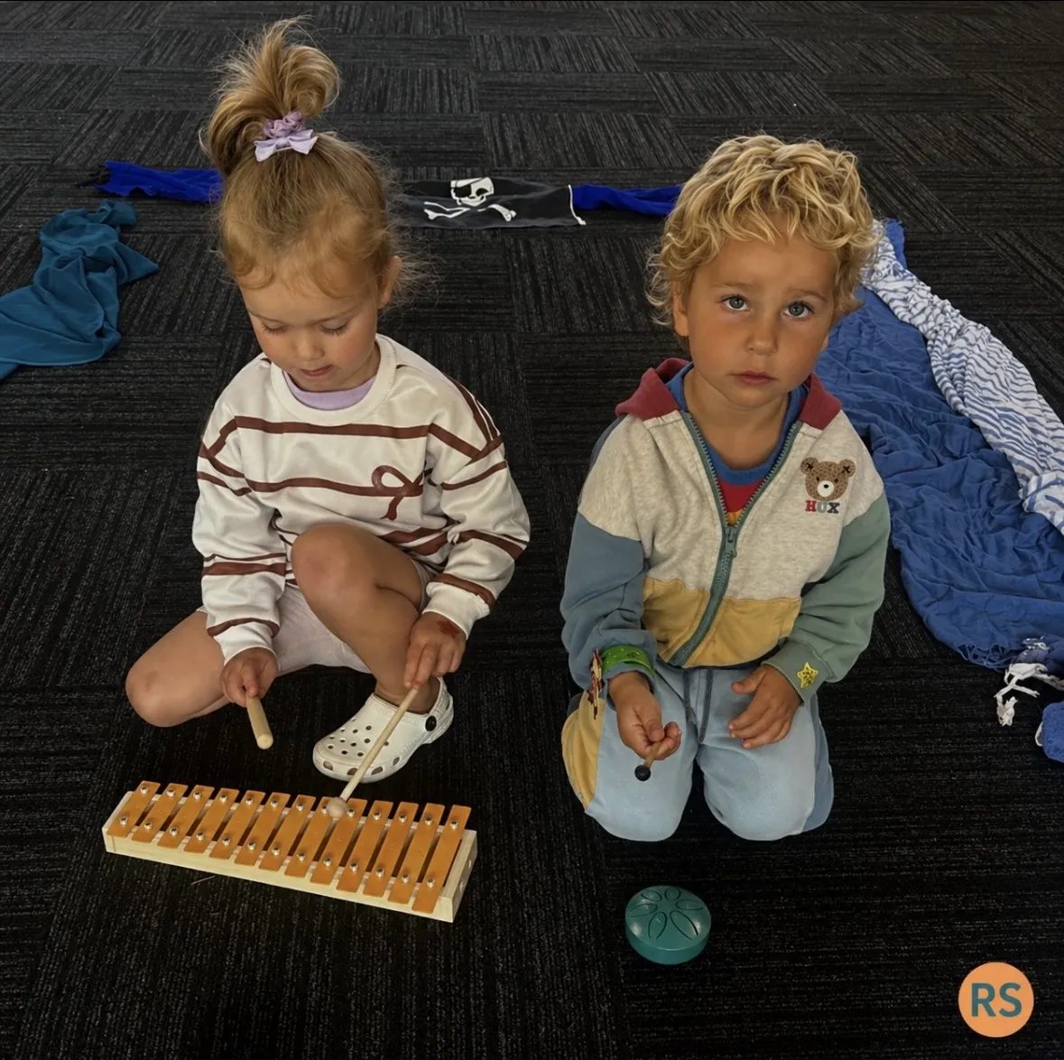 Two young children playing a glockenspiel together at a Tell & Show class
