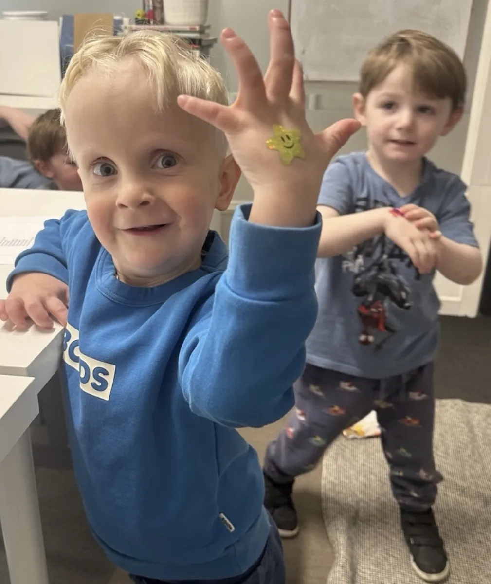Joyful young child with hands raised during a Tell & Show class at Ranges Studio