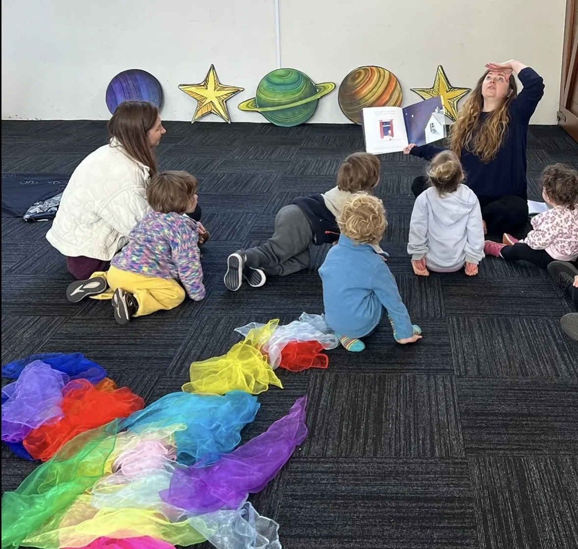 Young children exploring props on the mat during a Tell & Show class