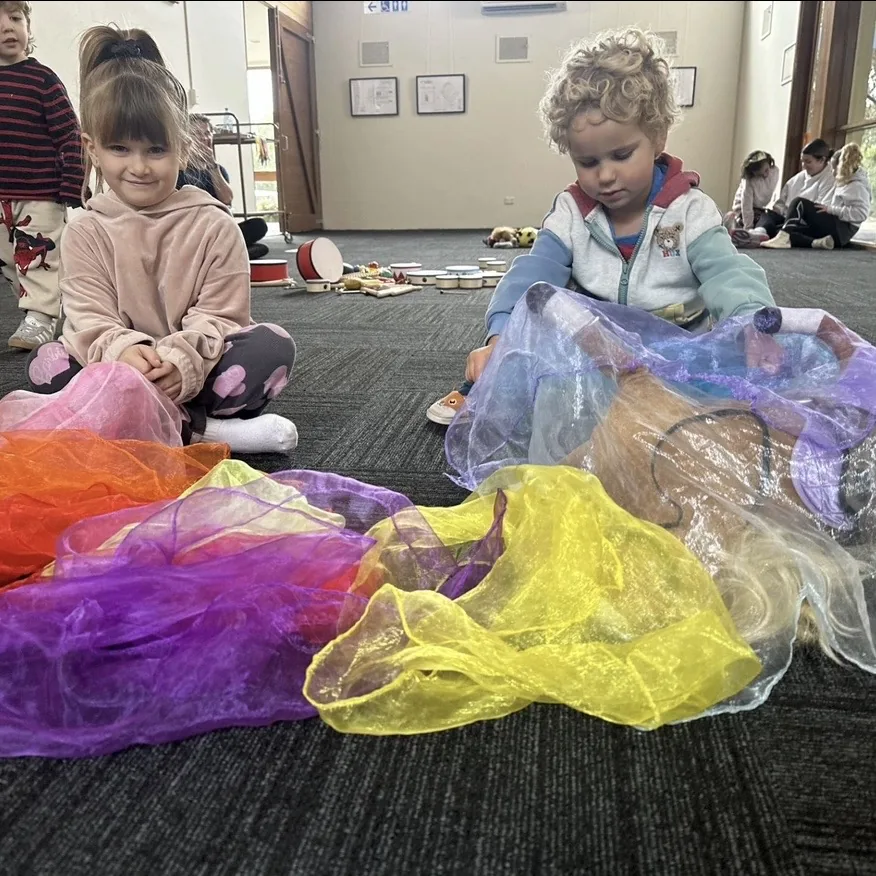 Two young children playing with rainbow tulle during a Tell & Show class at Ranges Studio