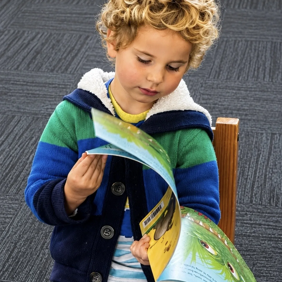 A young child bringing a story to life with a colourful picture book at a Tell & Show class